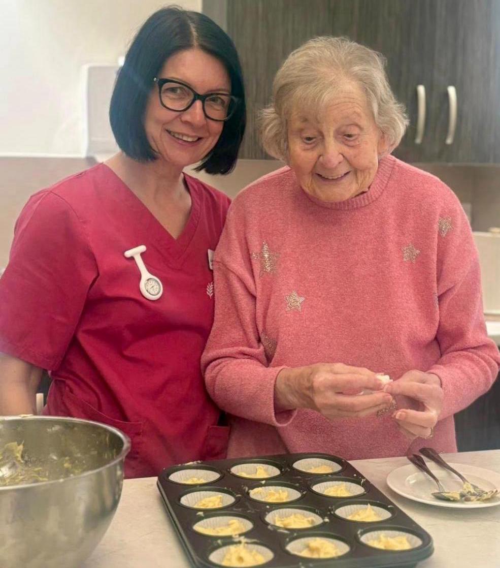Care home manager and resident smiling while baking cupcakes