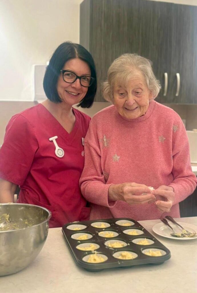 Care home resident and manager baking cupcakes