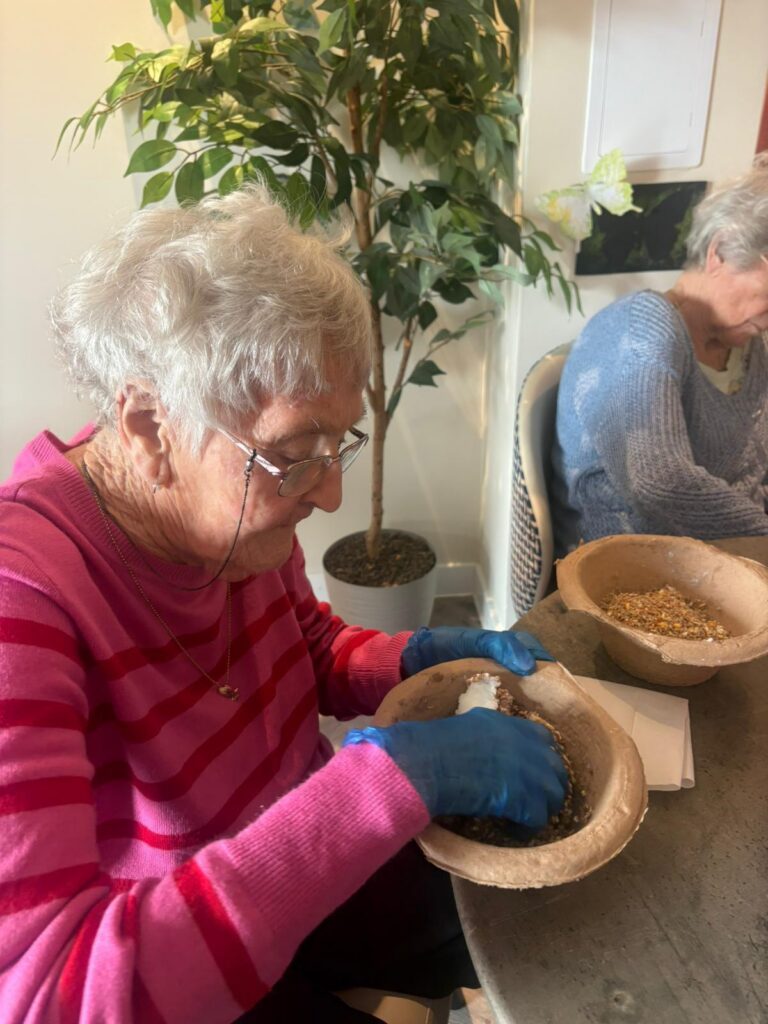 elderly woman plating seeds in a pot
