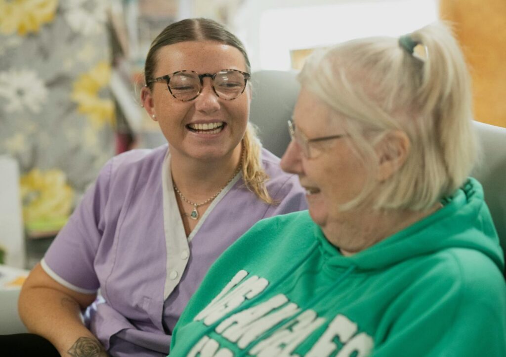 care home staff member smiling with an elderly resident