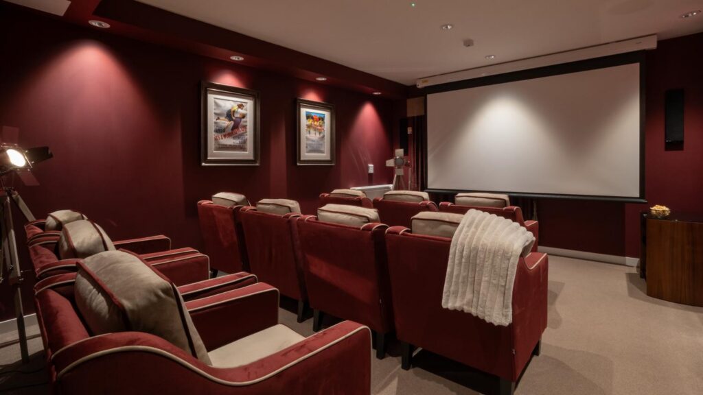 care home cinema room with a large screen, red walls and red armchairs
