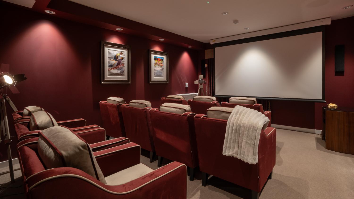 care home cinema room with a large screen, red walls and red armchairs