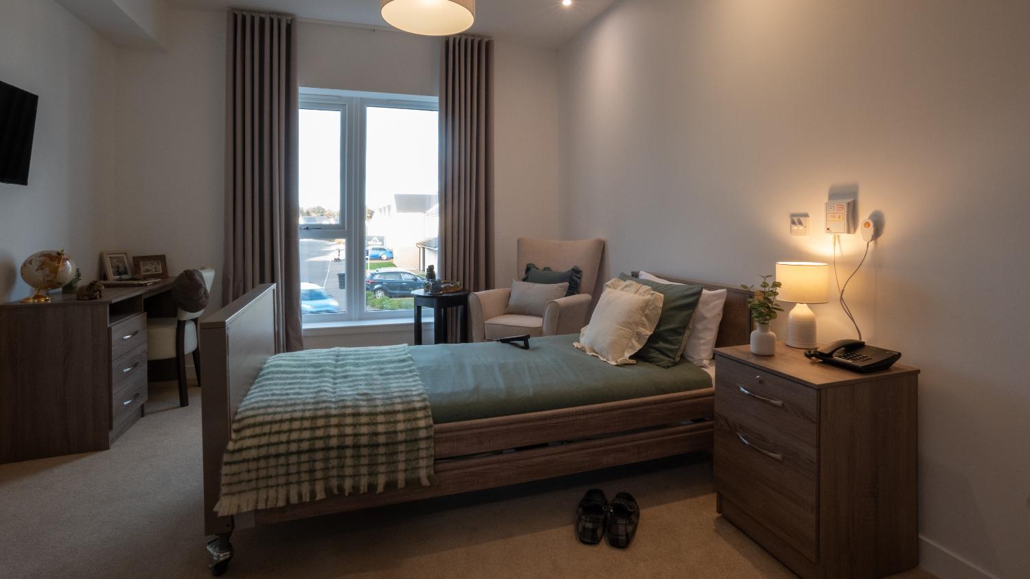 single profiling bed and wooden furniture in a care home bedroom