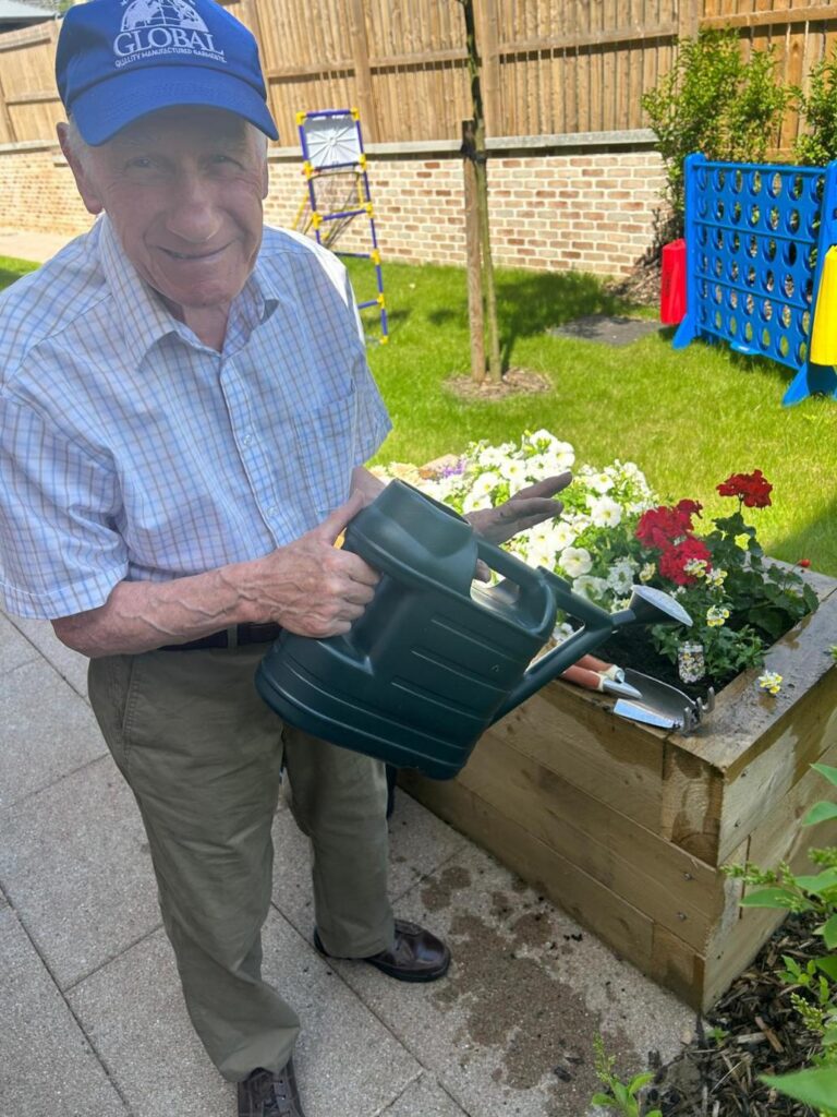 bill watering flowers in a planter