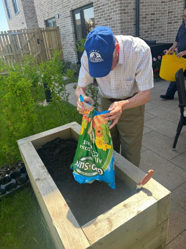 elderly man filling a raised planter with soil