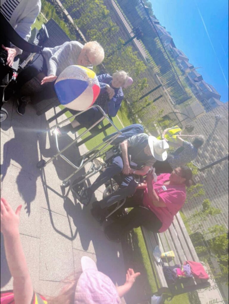 care home residents playing catch with children
