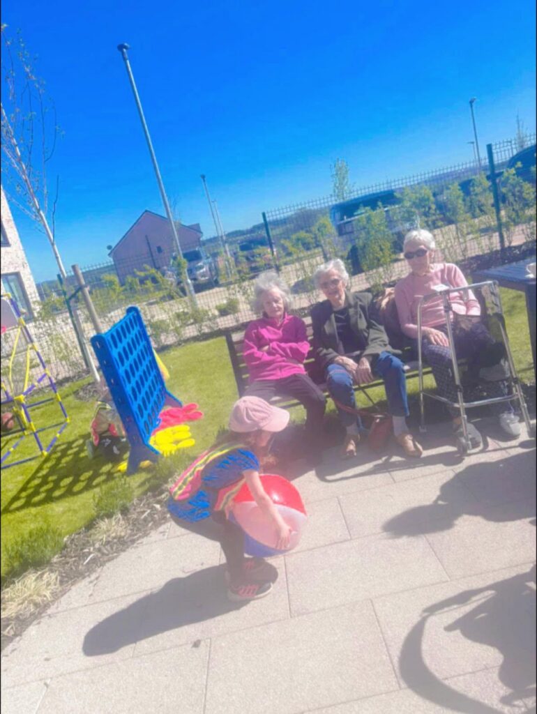 child throwing a beach ball to a care home resident