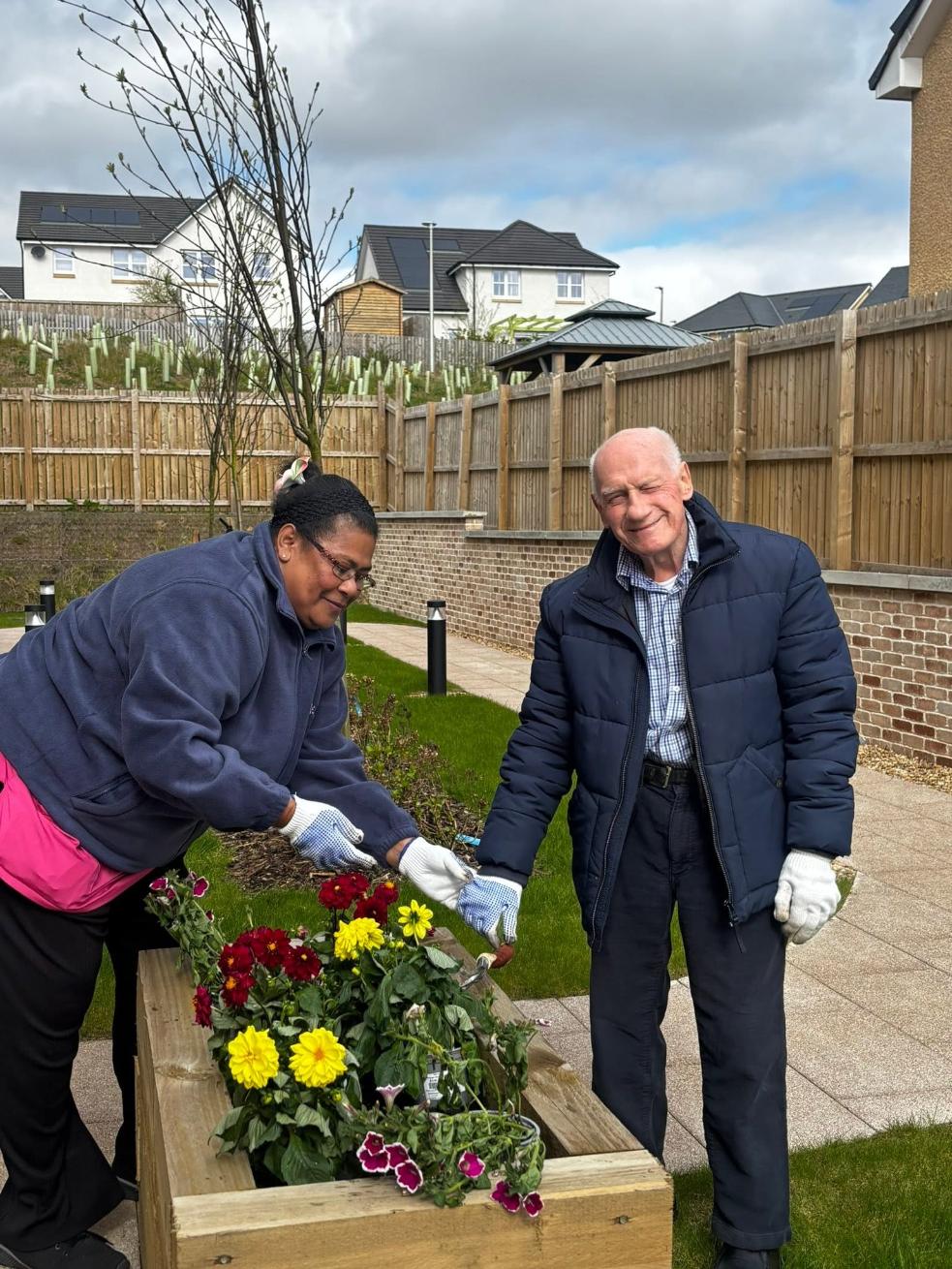 resident and care staff gardening flowers in raised outdoor planter