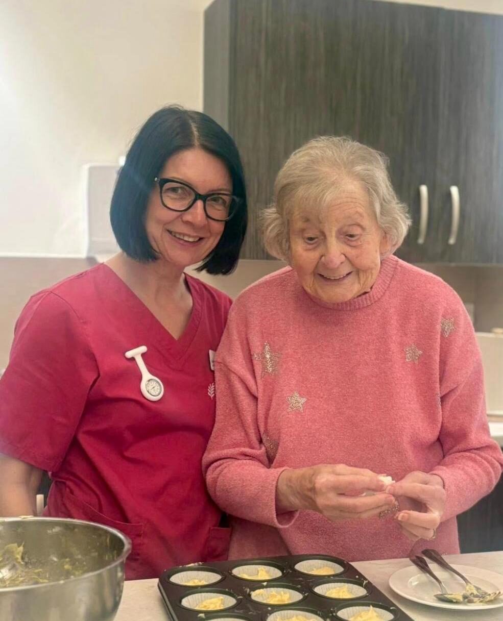care home resident baking cupcakes with staff