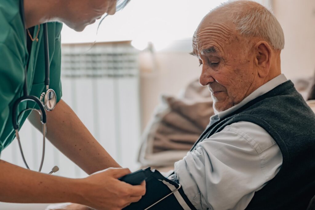 care home nurse checking an elderly man's blood pressure