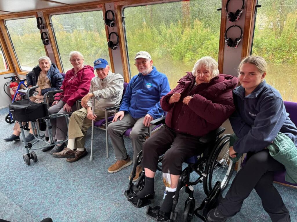 care home residents smiling inside a boat